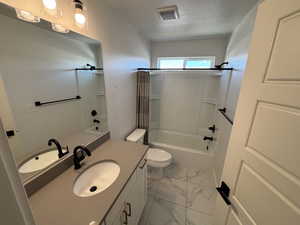 Full bath featuring shower / bath combination with curtain, vanity, light marble finish flooring, and a textured ceiling