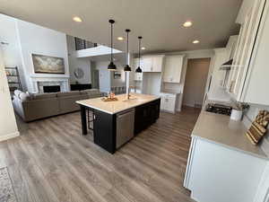 Kitchen with hanging light fixtures, a kitchen island with sink, light stone countertops, a kitchen bar, and dual tone cabinetry