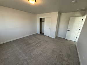 Unfurnished bedroom with carpet, a closet, and a textured ceiling