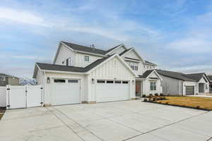 Modern inspired farmhouse featuring a gate, board and batten siding, driveway, roof with shingles, and a garage