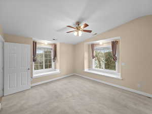 Spare room featuring lofted ceiling, ceiling fan, and light carpet