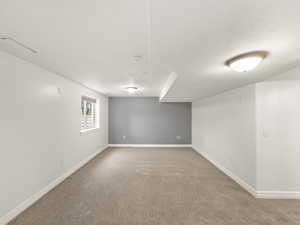 Basement featuring baseboards and light colored carpet