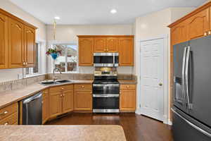 Kitchen featuring stainless steel appliances, wood finish cabinetry, dark wood-style floors, light countertops, and recessed lighting