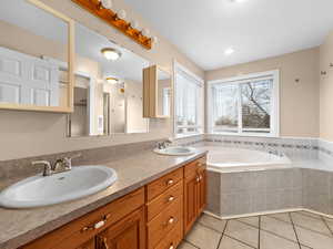 Bathroom with double vanity, a bath, and light tile patterned floors
