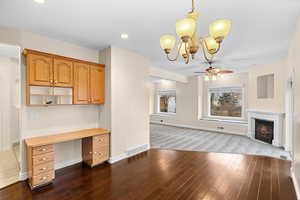 Unfurnished living room featuring a ceiling fan, dark wood-style flooring, a high end fireplace, and hanging lights