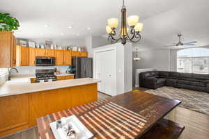 Kitchen featuring light countertops, vaulted ceiling, open floor plan, stainless steel appliances, and suspended lighting