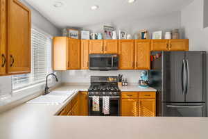 Kitchen featuring stainless steel appliances, light countertops, backsplash, recessed lighting, and wood finish cabinets