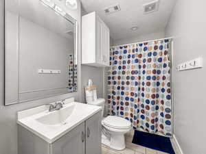 Full bathroom featuring vanity, a shower with curtain, and a textured ceiling