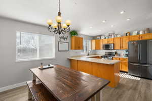 Kitchen with stainless steel appliances, light countertops, dark wood-style floors, lofted ceiling, and hanging lights