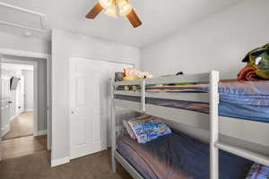 Bedroom with dark colored carpet, a ceiling fan, and a closet