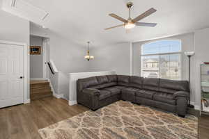 Living area featuring wood finished floors, hanging lights, a ceiling fan, and lofted ceiling