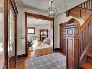 Entryway with wood finished floors, a chandelier, and a fireplace
