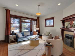 Living area with wood finished floors, a fireplace with flush hearth, and recessed lighting