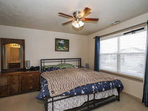 Bedroom featuring carpet flooring, a textured ceiling, and ceiling fan