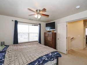 Bedroom with light carpet, a textured ceiling, and a ceiling fan