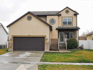 Traditional-style home with brick siding, driveway, a garage, and stucco siding