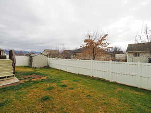 Fenced backyard featuring a storage unit and a residential view