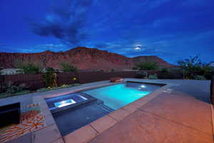 Integrated pool / hot tub with a fenced backyard, a patio, and a mountain view