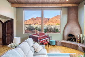 Living area featuring a large fireplace, hardwood / wood-style flooring, a mountain view, a wooden ceiling with exposed beams, and healthy amount of natural light