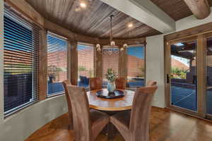 Dining area with a wood ceiling with exposed beams, suspended lighting, and wood finished floors