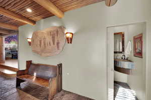 Hall with a wood ceiling with exposed beams and stone finish floors