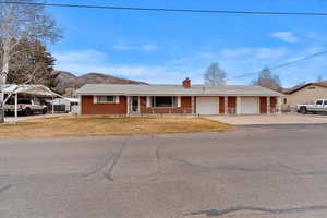 Single story home featuring a chimney, a porch, brick siding, a mountain view, and driveway