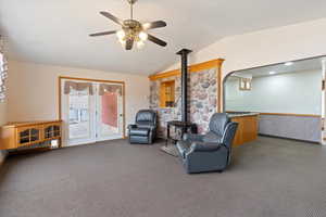 Sitting room with carpet floors, lofted ceiling, a wood stove, ceiling fan, and arched walkways