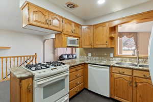 Kitchen with white appliances, light stone counters, open shelves, backsplash, and wood finish cabinetry