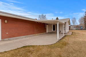 Rear view of house with a lawn, a patio, brick siding, and a playground