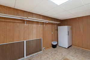 Laundry room with a drop ceiling and wooden walls