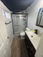 Full bath with dark wood-style flooring, vanity, and a stall shower