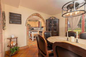 Dining room featuring suspended lighting, light tile patterned flooring, and arched walkways