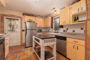 Kitchen featuring open shelves, stainless steel appliances, tasteful backsplash, cream cabinets, and light floors