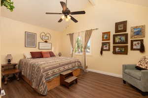 Bedroom featuring dark wood-type flooring, vaulted ceiling with beams, and ceiling fan