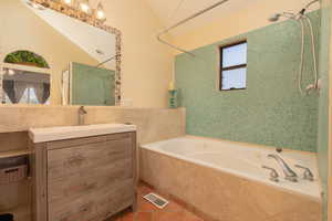 Full bathroom featuring tiled shower / bath, vanity, lofted ceiling, and light tile patterned floors