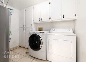 Laundry room featuring cabinet space, light tile patterned floors, and washer and dryer