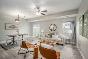 Living room featuring LVP flooring, a ceiling fan, and healthy amount of natural light