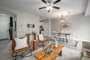 Living area featuring arched walkways, light wood-style floors, and ceiling fan