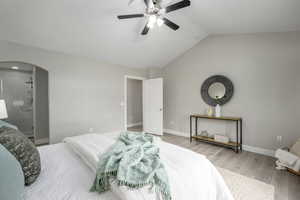 Bedroom featuring arched walkways, wood finished floors, and ceiling fan