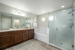 Bathroom with a stall shower, vanity, light wood-style flooring, a garden tub, and recessed lighting