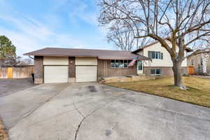 Tri-level home featuring brick siding, driveway, and a garage