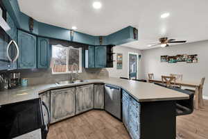 Kitchen featuring a peninsula, ceiling fan, stainless steel appliances, light wood-style flooring, and recessed lighting
