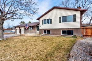 View of front of home with brick siding, a garage, a chimney, and concrete driveway