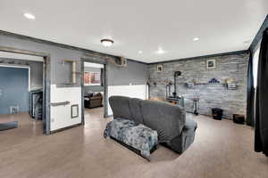 Living area with brick wall, crown molding, a wood stove, recessed lighting, and wood finished floors