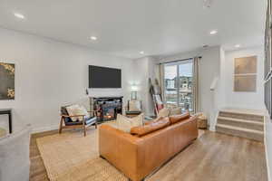Living room with light wood-style flooring, a glass covered fireplace, and recessed lighting