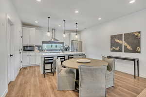Dining area with light wood finished floors and recessed lighting