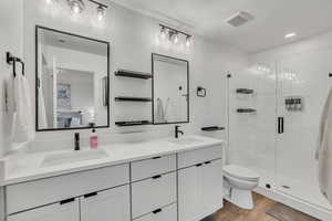 Ensuite bathroom featuring double vanity, a stall shower, light wood finished floors, and recessed lighting