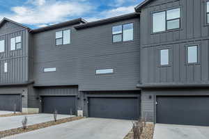 View of side of home featuring board and batten siding, concrete driveway, and a garage