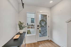 Doorway to outside with wood finished floors and baseboards