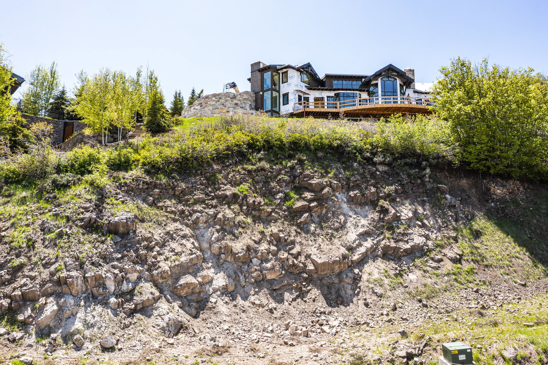 Hillside property featuring a multi-level structure with extensive decking, large windows, and a stone chimney